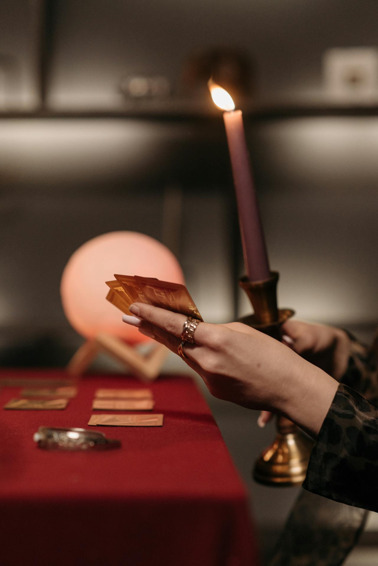 A hand holding a tarot card and a candle