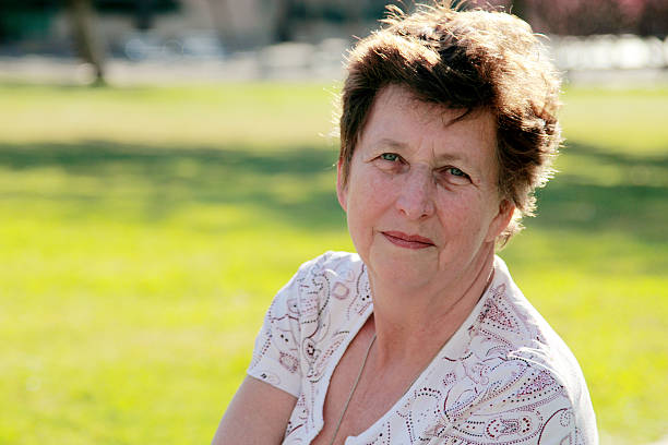 Photo of short haired elderly woman sitting on the lawn