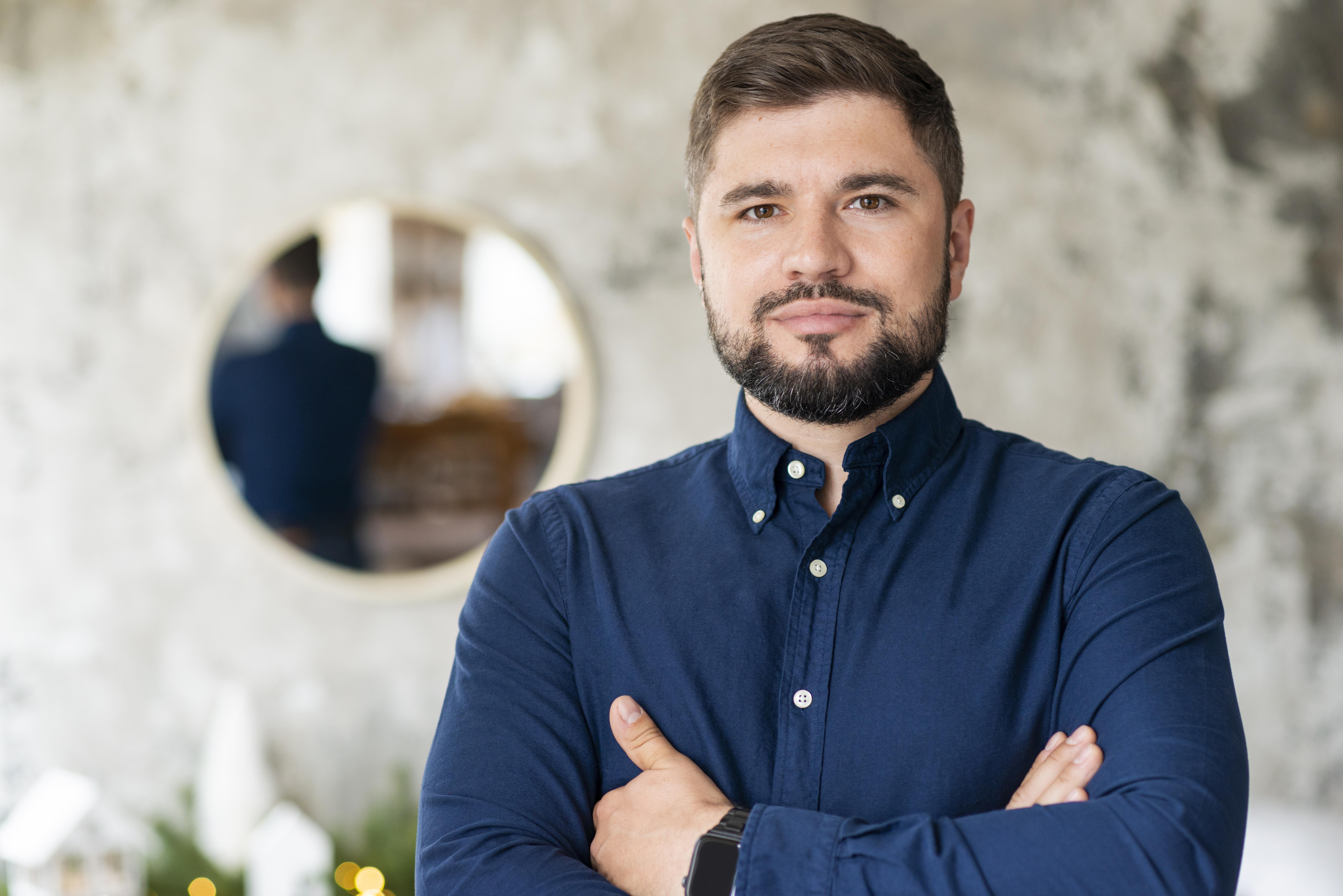 Photo of a man with a beard in a blue shirt